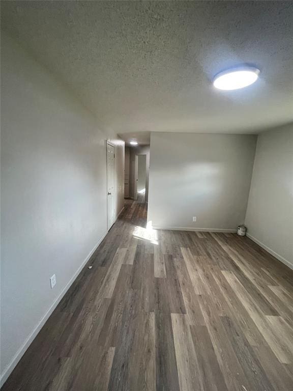 spare room with a textured ceiling and dark wood-type flooring