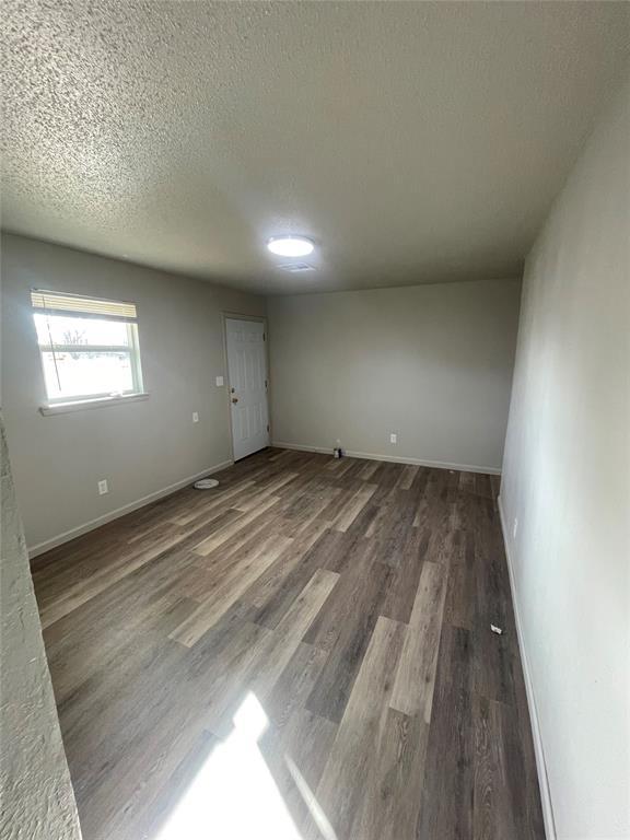 spare room featuring a textured ceiling and dark wood-type flooring