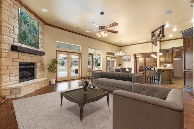 living room featuring crown molding, a stone fireplace, dark hardwood / wood-style floors, and ceiling fan with notable chandelier