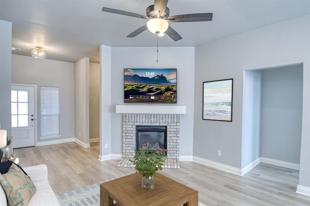 living room with ceiling fan, a fireplace, and light hardwood / wood-style floors