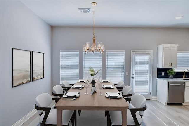 dining room with sink, an inviting chandelier, and light hardwood / wood-style flooring