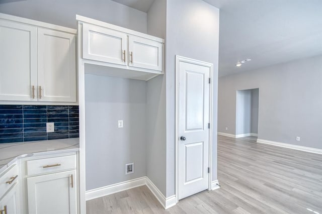 kitchen featuring light stone counters, backsplash, light hardwood / wood-style flooring, and white cabinets