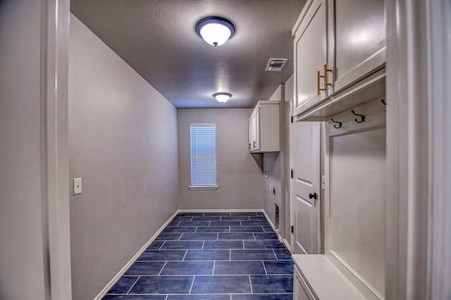 clothes washing area featuring cabinets and a textured ceiling