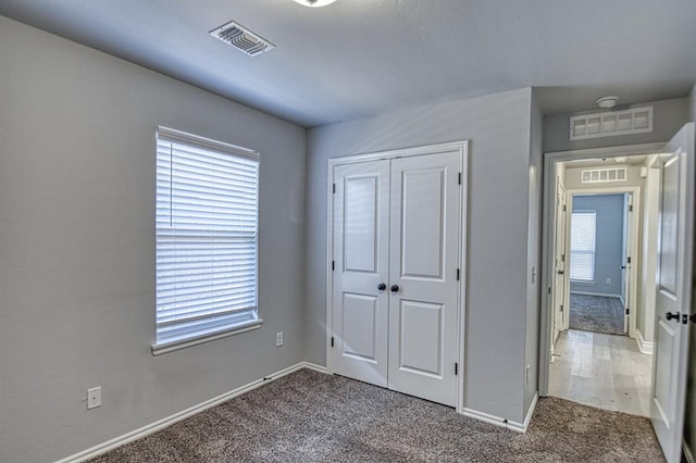 unfurnished bedroom with multiple windows, carpet, and a closet