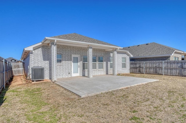 rear view of house with central AC, a lawn, and a patio area