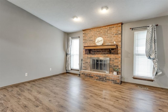 unfurnished living room with hardwood / wood-style flooring, a fireplace, and vaulted ceiling