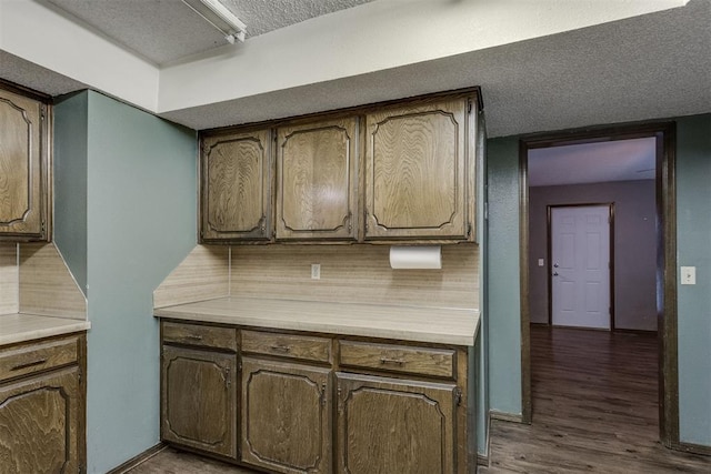 kitchen featuring decorative backsplash, a textured ceiling, and dark hardwood / wood-style flooring