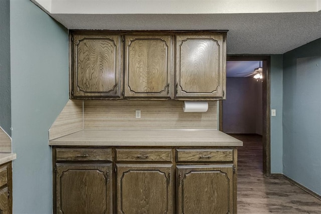 kitchen featuring decorative backsplash, ceiling fan, dark wood-type flooring, and a textured ceiling