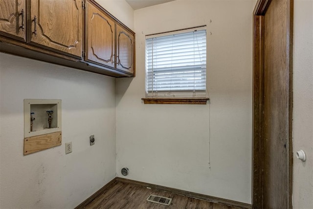 clothes washing area featuring electric dryer hookup, cabinets, dark hardwood / wood-style floors, and washer hookup