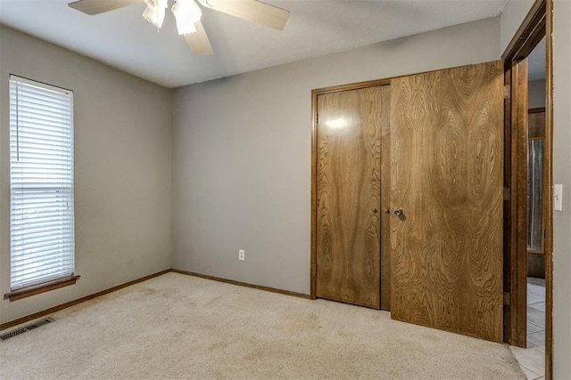 unfurnished bedroom with ceiling fan, light colored carpet, and a closet