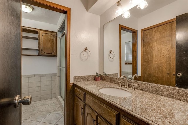 bathroom with tile patterned flooring, vanity, and a shower with door