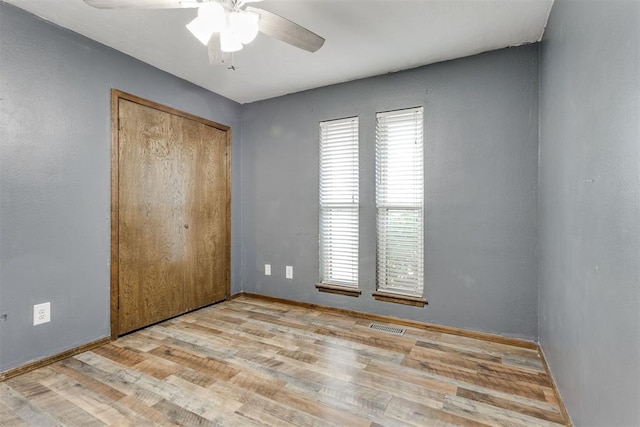 unfurnished bedroom featuring light hardwood / wood-style flooring, a closet, and ceiling fan