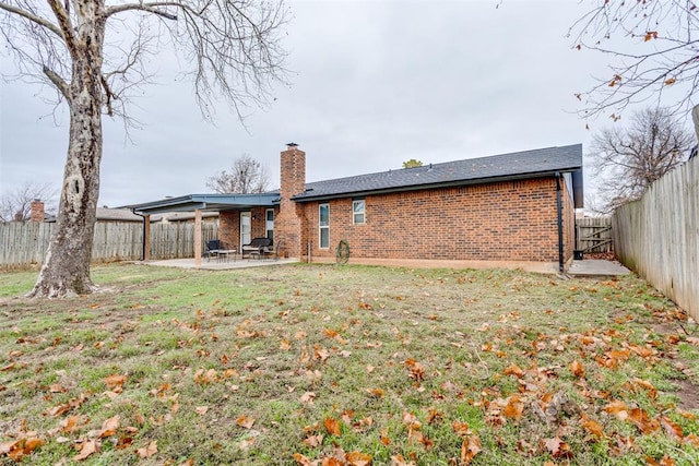 rear view of house featuring a lawn and a patio