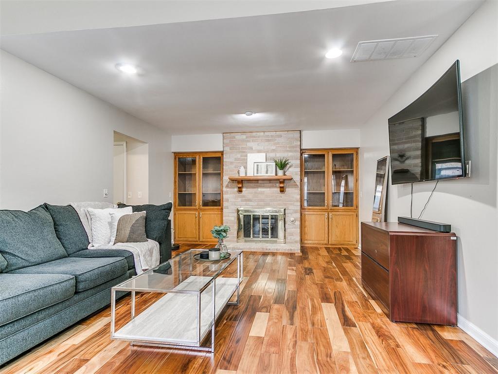 living room featuring a brick fireplace and light wood-type flooring