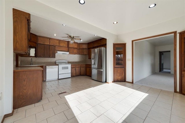 kitchen featuring ceiling fan, light colored carpet, white appliances, and sink