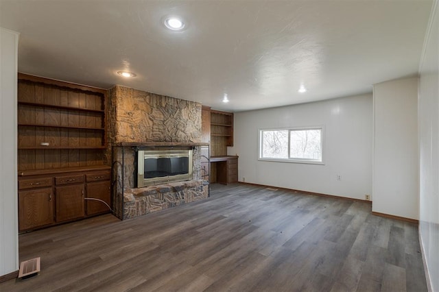 unfurnished living room featuring a fireplace, dark hardwood / wood-style floors, and built in features