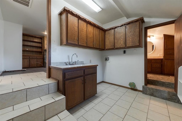 kitchen with vaulted ceiling with beams, sink, light tile patterned floors, and dark brown cabinets