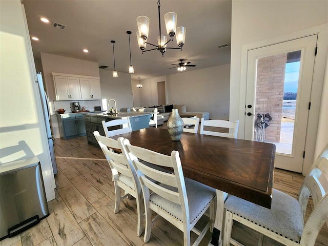 dining room with ceiling fan with notable chandelier and sink