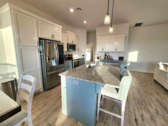 kitchen featuring sink, decorative backsplash, dark stone countertops, white cabinetry, and stainless steel appliances