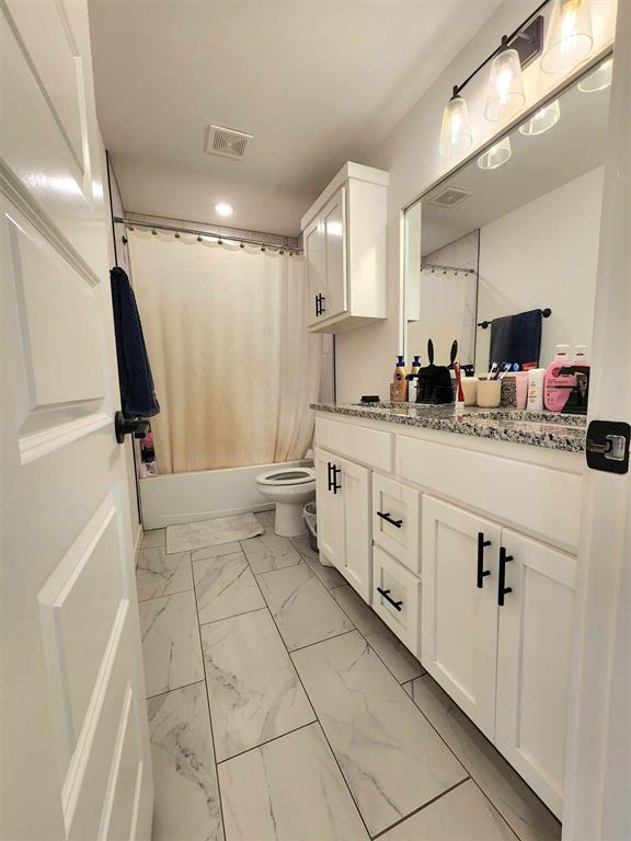 full bathroom featuring vanity, shower / bath combo, and toilet