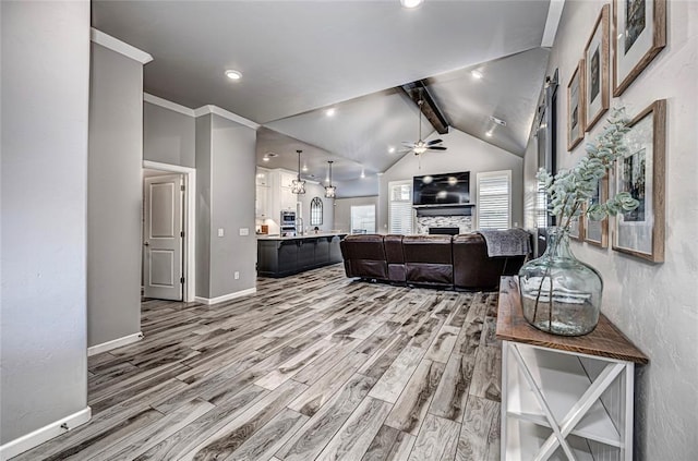 living room featuring lofted ceiling with beams, ceiling fan, a fireplace, and wood-type flooring