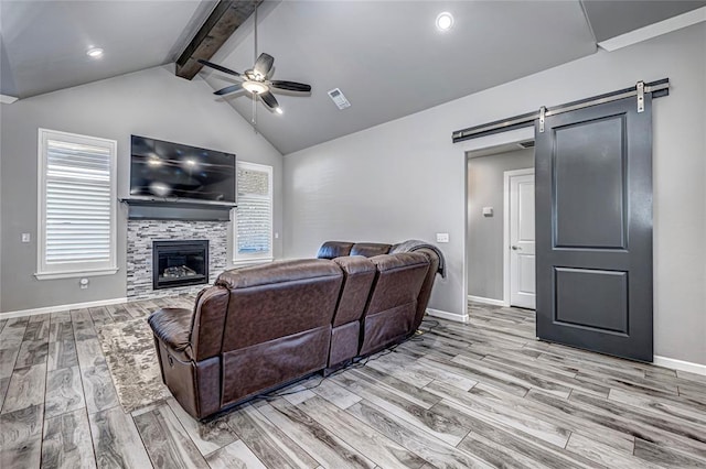 living room with a fireplace, a barn door, light hardwood / wood-style floors, and ceiling fan