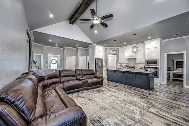 living room featuring ceiling fan, sink, vaulted ceiling with beams, light hardwood / wood-style flooring, and ornamental molding