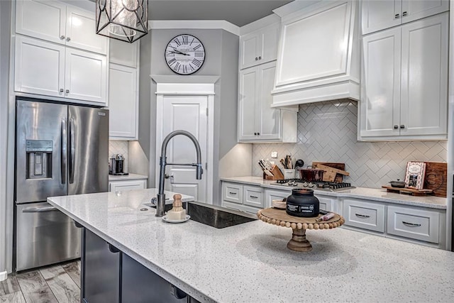 kitchen featuring light stone countertops, appliances with stainless steel finishes, custom exhaust hood, white cabinetry, and hanging light fixtures