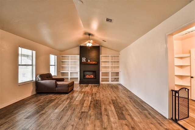 unfurnished room featuring hardwood / wood-style floors, a large fireplace, ceiling fan, and built in shelves