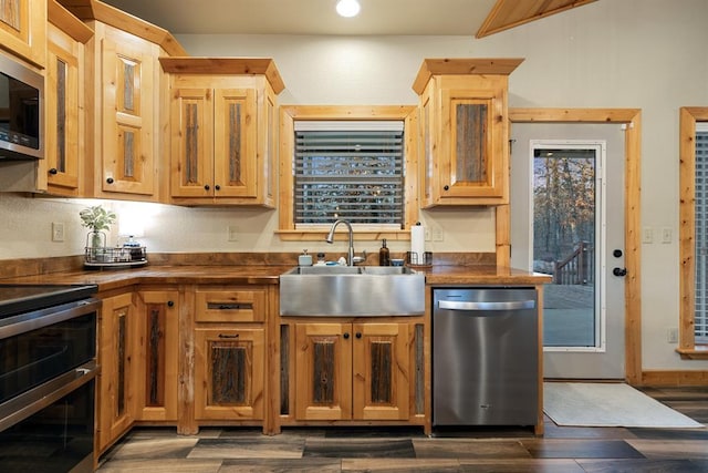 kitchen featuring stainless steel appliances, dark hardwood / wood-style floors, butcher block counters, and sink