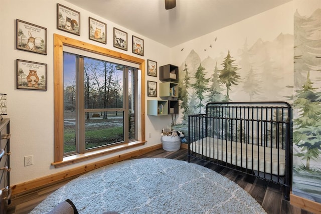 bedroom with multiple windows, dark hardwood / wood-style floors, a nursery area, and ceiling fan