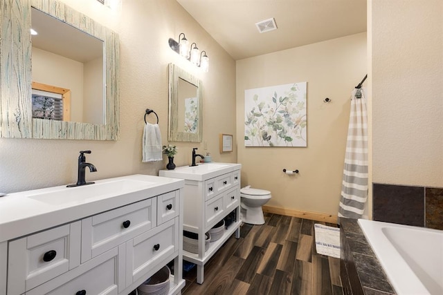 bathroom with hardwood / wood-style floors, vanity, toilet, and tiled tub