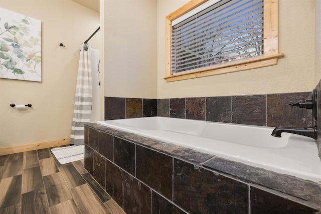 bathroom with a relaxing tiled tub and hardwood / wood-style flooring