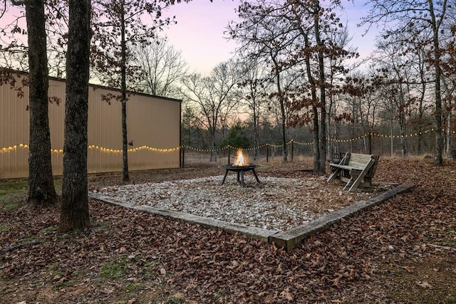 yard at dusk featuring an outdoor fire pit