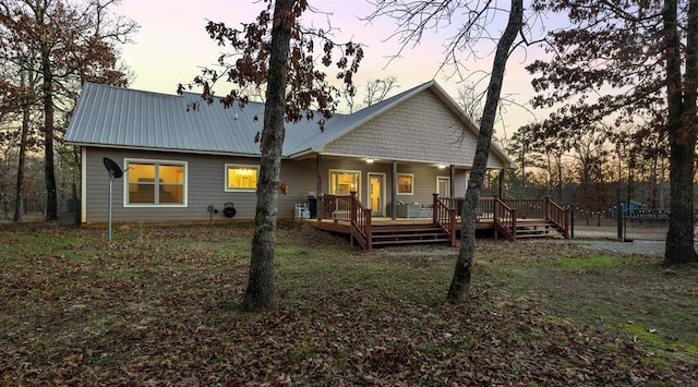 back house at dusk featuring covered porch