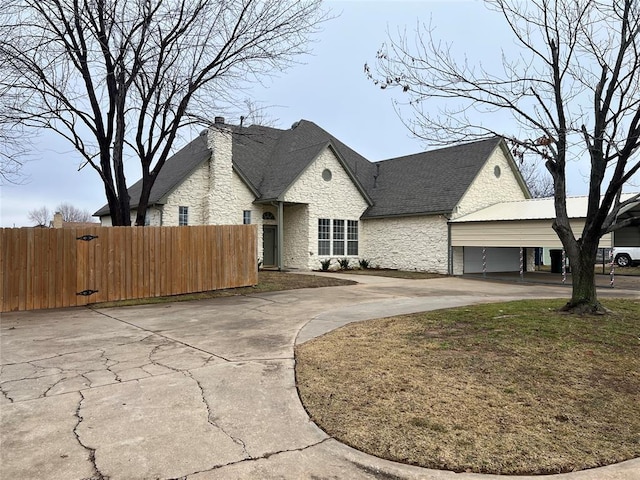 french country inspired facade featuring stone siding, driveway, a chimney, and fence