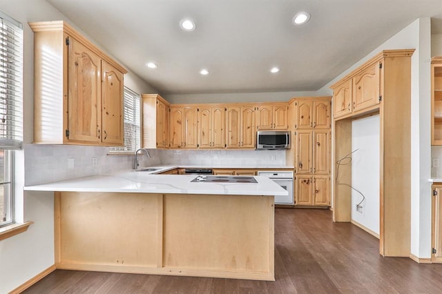 kitchen with stainless steel microwave, light brown cabinets, a sink, oven, and a peninsula