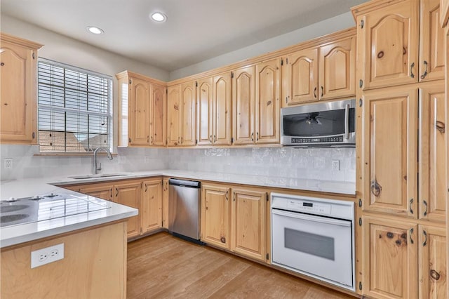 kitchen with light wood finished floors, appliances with stainless steel finishes, light countertops, light brown cabinetry, and a sink