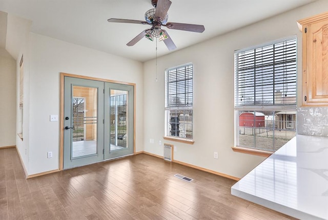 unfurnished dining area featuring a ceiling fan, wood finished floors, visible vents, and baseboards