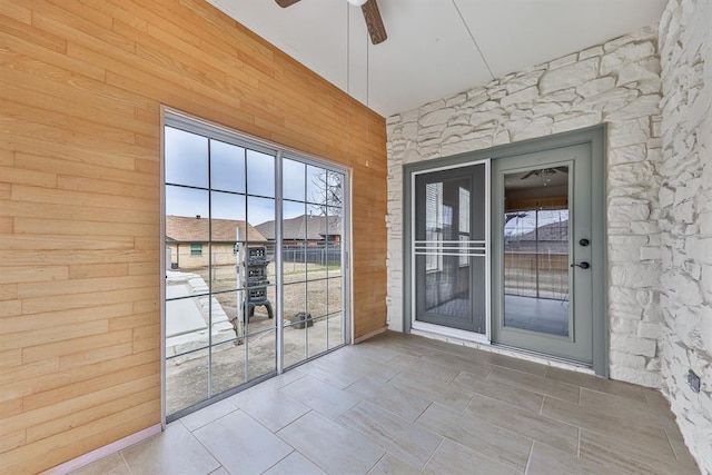 doorway to outside featuring wood walls and ceiling fan