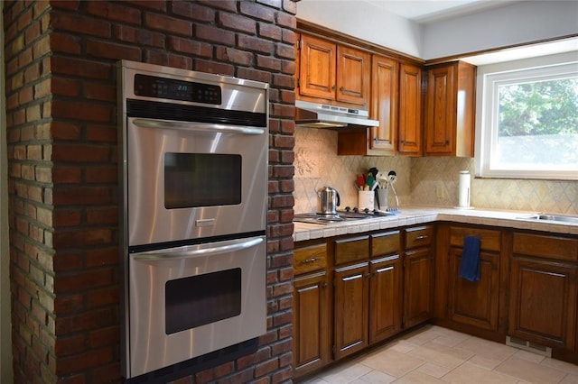 kitchen featuring decorative backsplash, appliances with stainless steel finishes, and tile counters