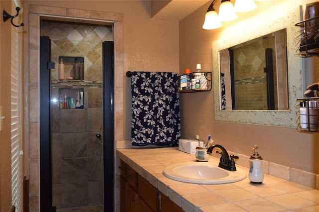 bathroom with tiled shower and vanity