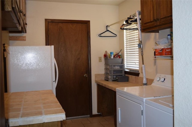 clothes washing area featuring light tile patterned flooring, cabinets, and independent washer and dryer