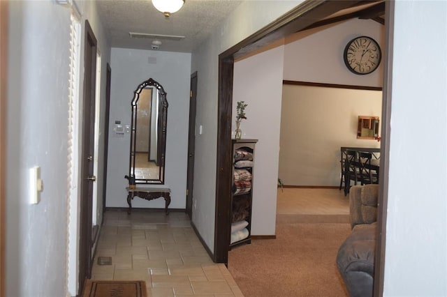 hallway featuring light colored carpet and a textured ceiling