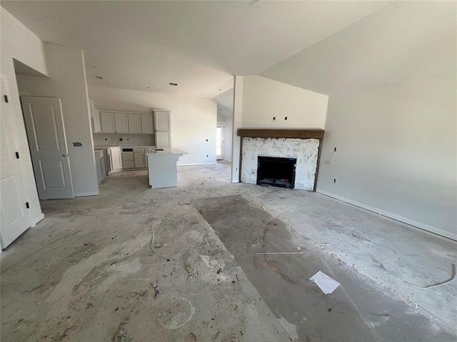 unfurnished living room featuring vaulted ceiling, a fireplace, and baseboards