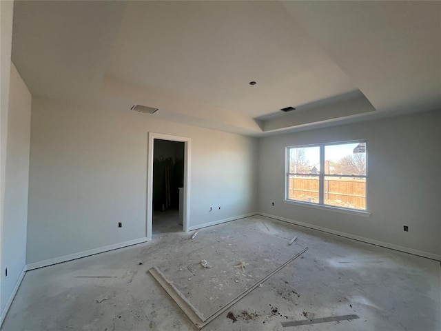 empty room featuring baseboards, visible vents, and a raised ceiling