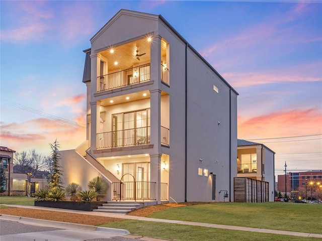 view of front of house with a lawn and a balcony