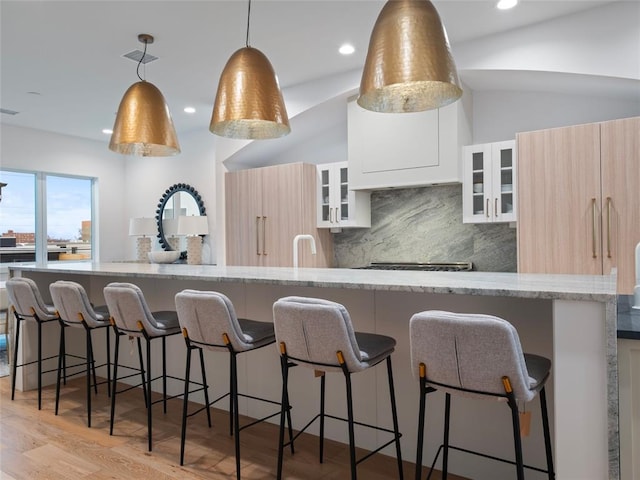 kitchen with decorative backsplash, light stone counters, lofted ceiling, and decorative light fixtures