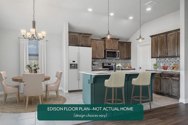 kitchen featuring decorative backsplash, vaulted ceiling, a kitchen island with sink, white refrigerator with ice dispenser, and hanging light fixtures