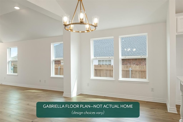 unfurnished dining area with hardwood / wood-style floors, lofted ceiling, and a chandelier